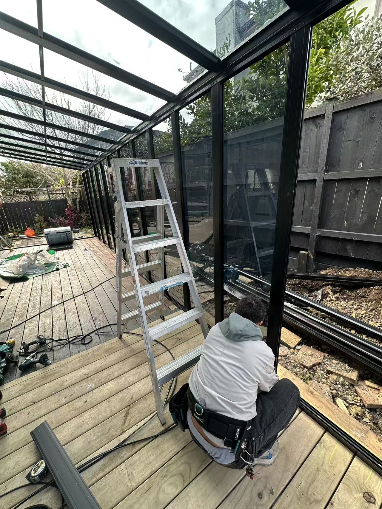 Auckland installer fitting glazing panels to a custom outdoor structure
