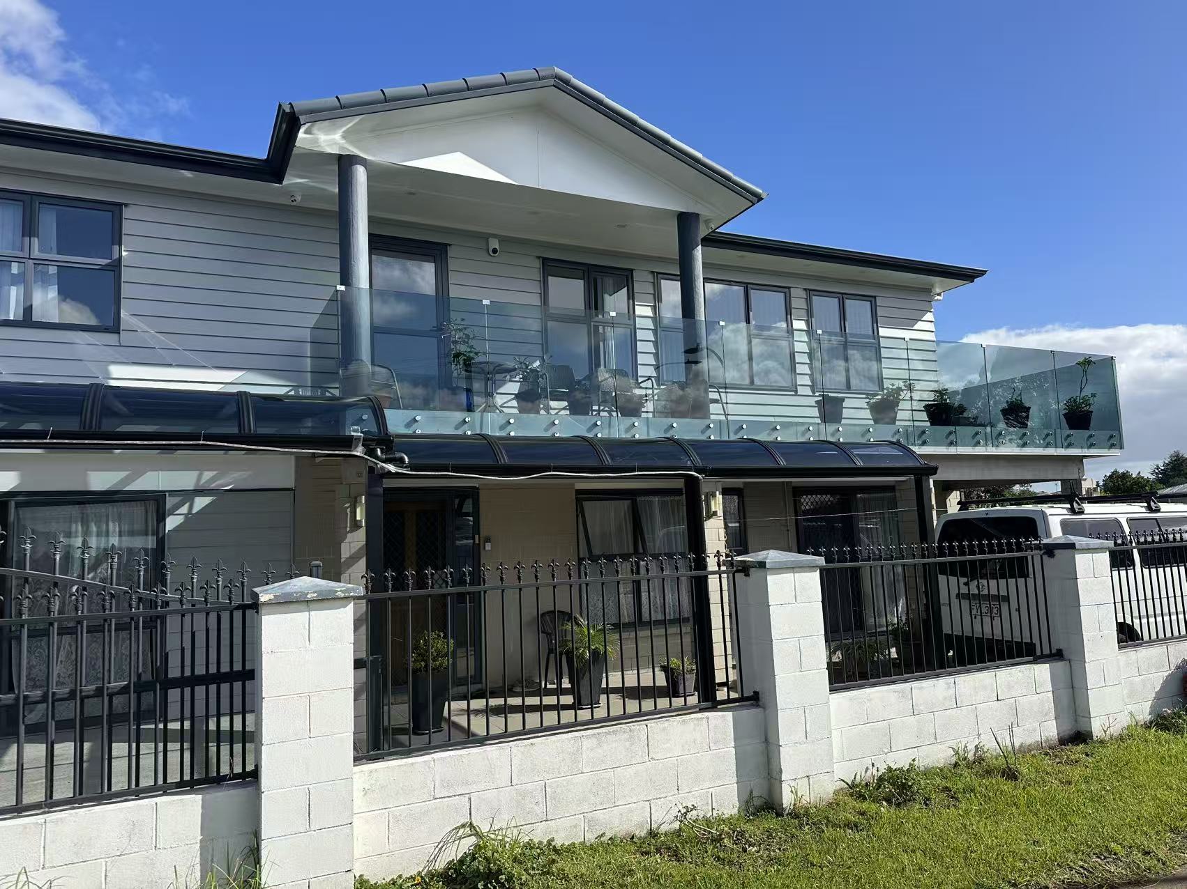 Dark curved polycarbonate patio canopies on a two-storey Auckland home